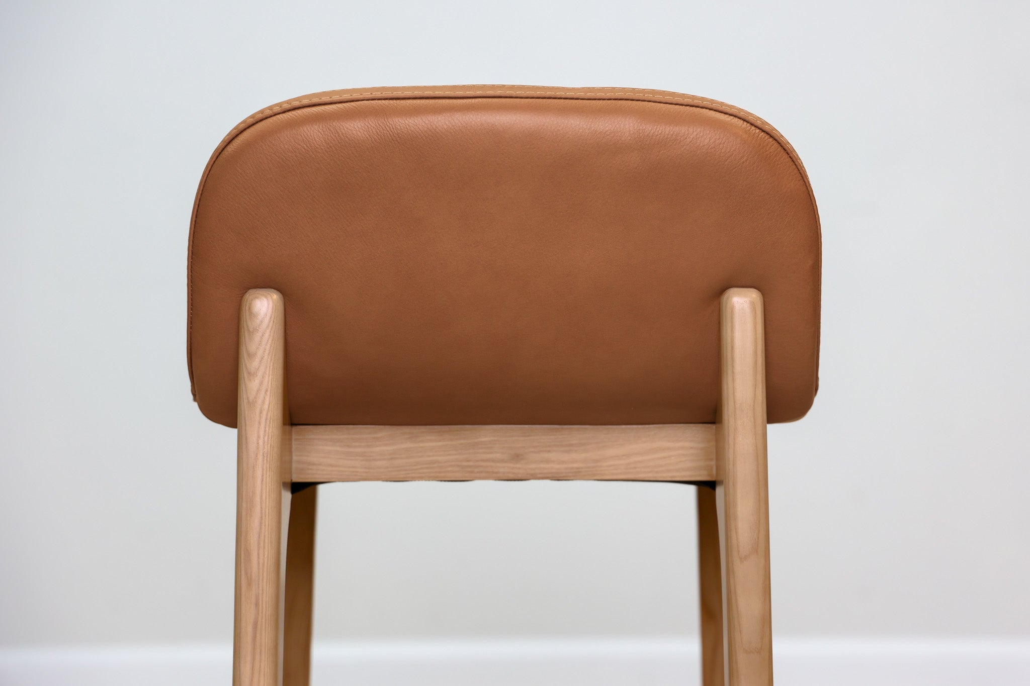 Sable counter stool in cognac leather with a low back and natural wood legs with stretchers, kitchen counter