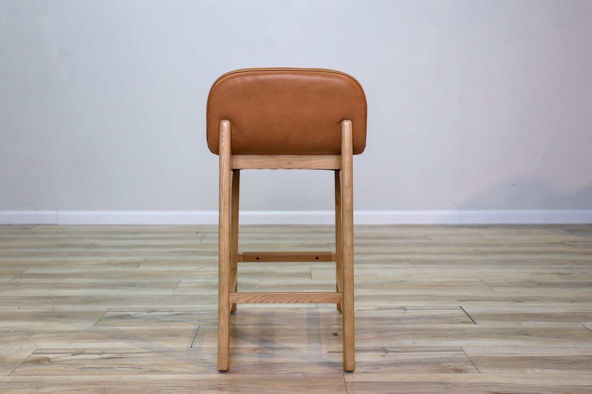 Sable counter stool in cognac leather with a low back and natural wood legs with stretchers, kitchen counter