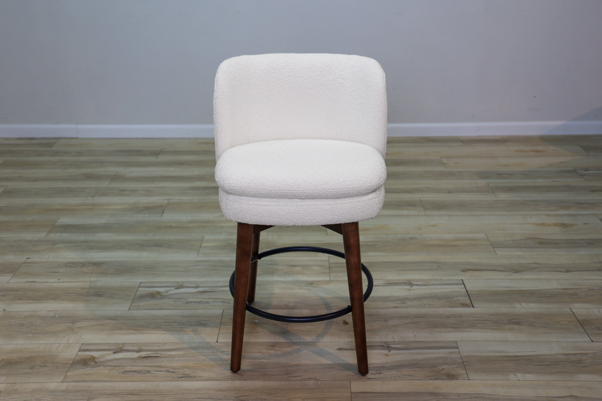 Avalon swivel counter stool in cream bouclé performance fabric with walnut wood legs and a black ring footrest, kitchen counter