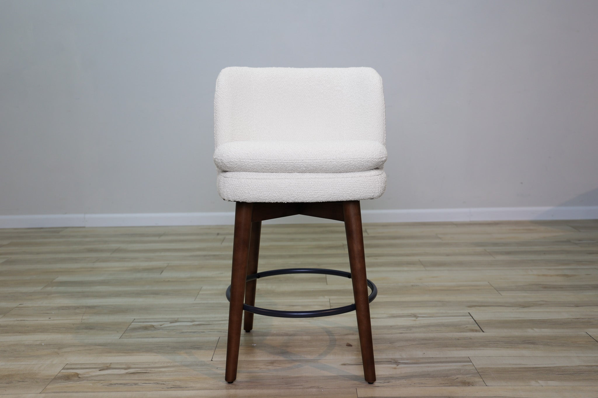 Avalon swivel counter stool in cream bouclé performance fabric with walnut wood legs and a black ring footrest, kitchen counter