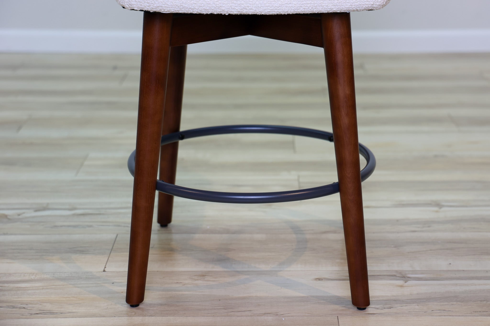 Avalon swivel counter stool in cream bouclé performance fabric with walnut wood legs and a black ring footrest, kitchen counter