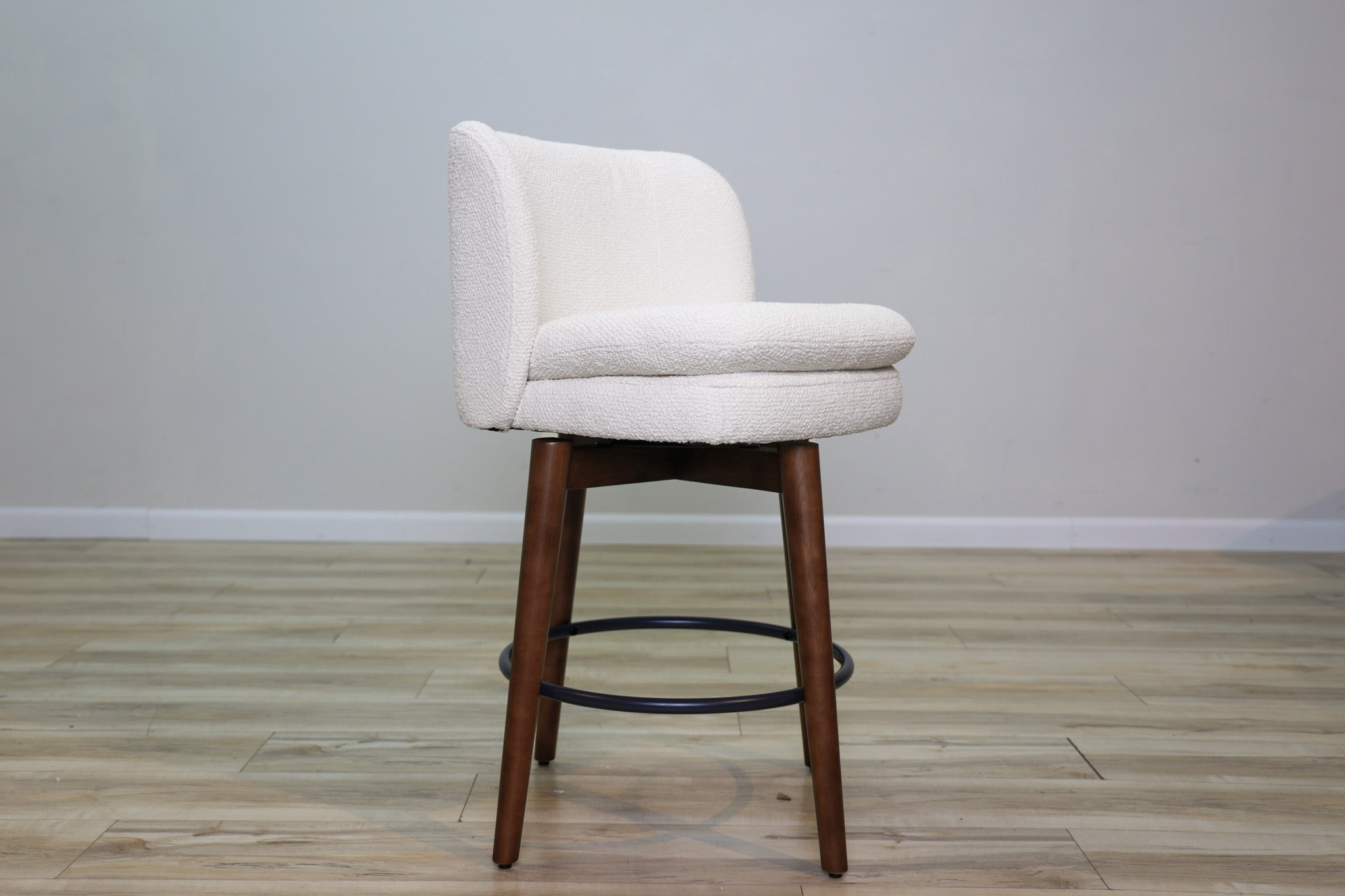 Avalon swivel counter stool in cream bouclé performance fabric with walnut wood legs and a black ring footrest, kitchen counter