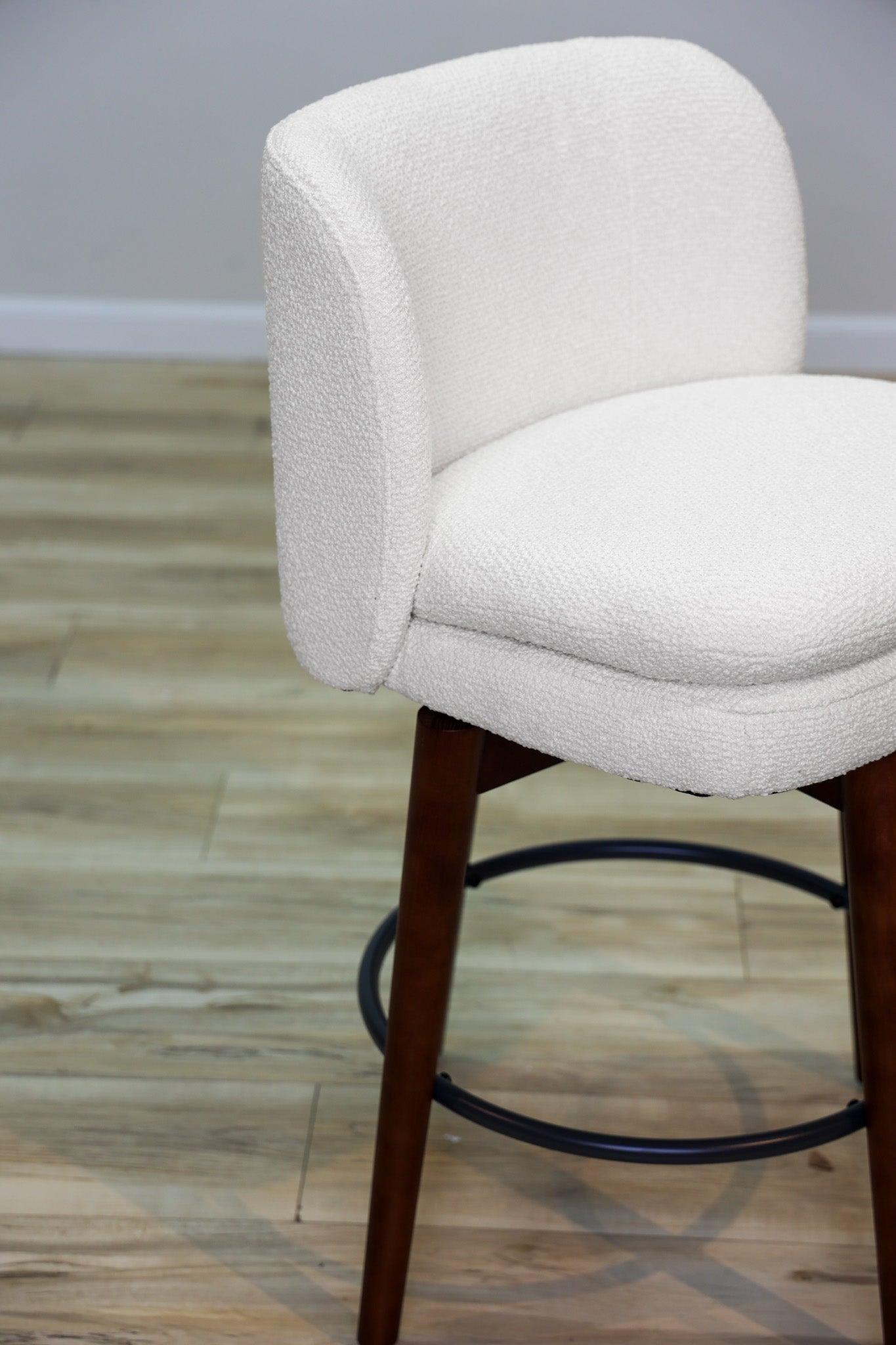 Avalon swivel counter stool in cream bouclé performance fabric with walnut wood legs and a black ring footrest, kitchen counter
