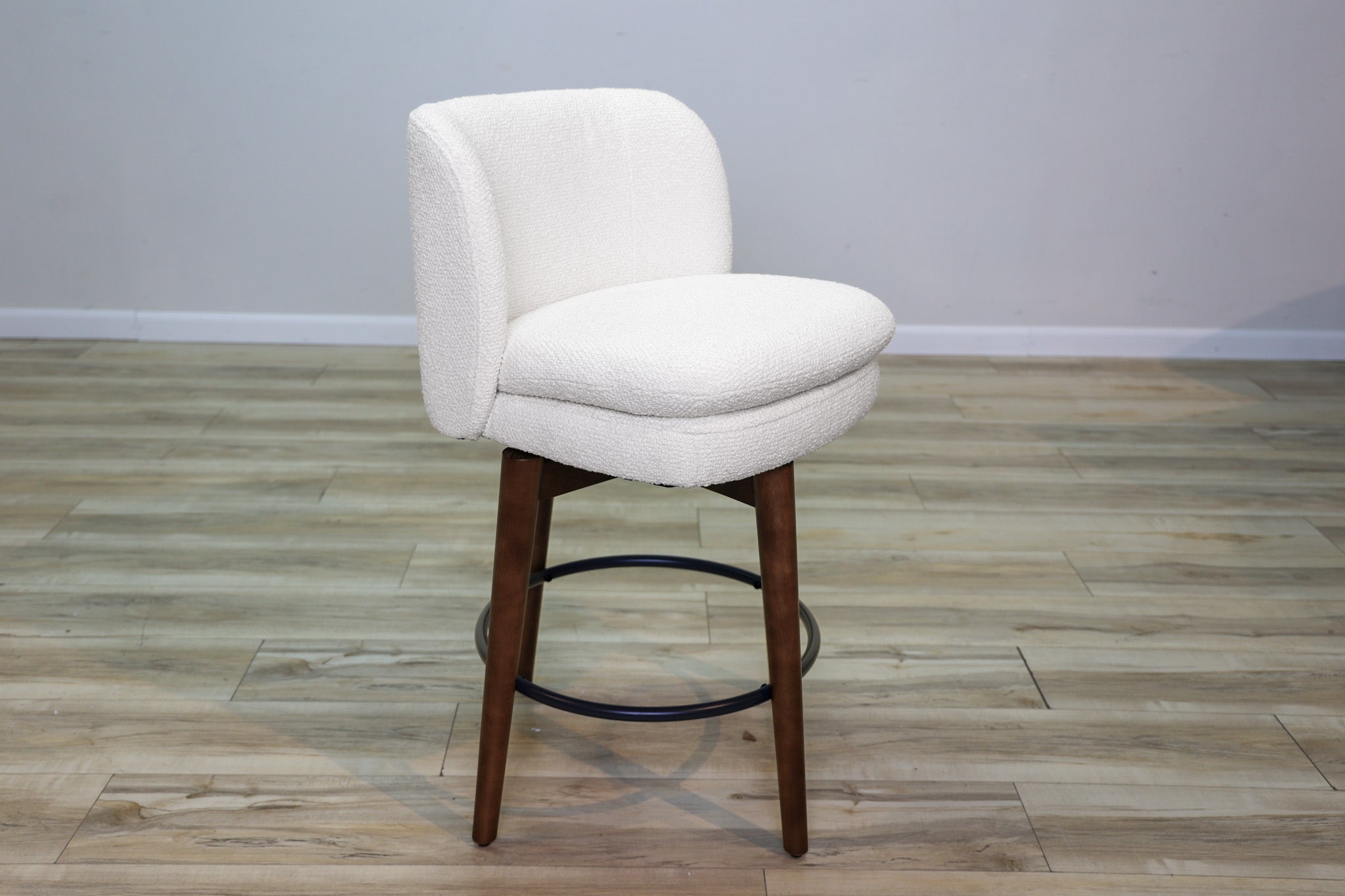 Avalon swivel counter stool in cream bouclé performance fabric with walnut wood legs and a black ring footrest, kitchen counter