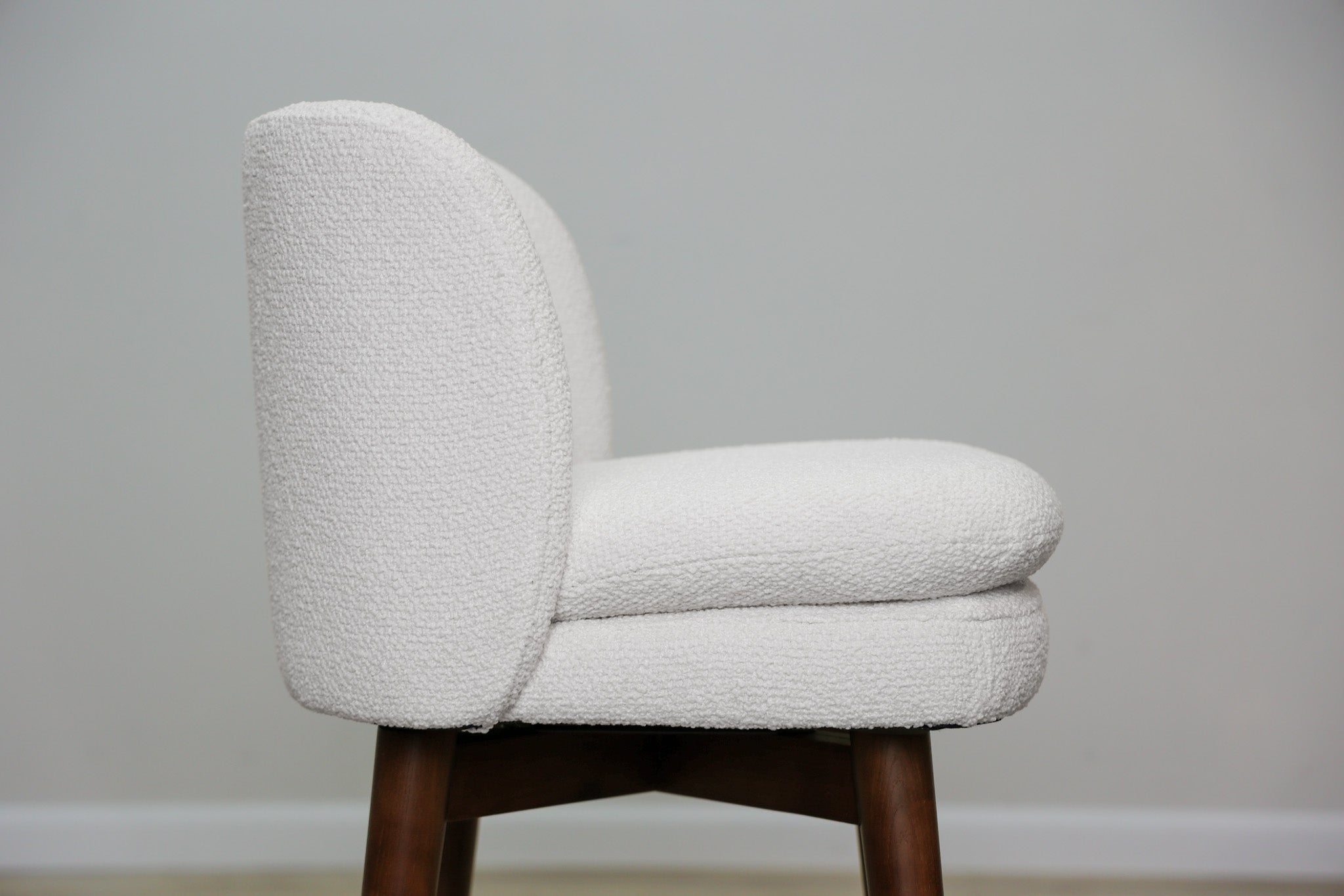 Avalon swivel counter stool in cream bouclé performance fabric with walnut wood legs and a black ring footrest, kitchen counter