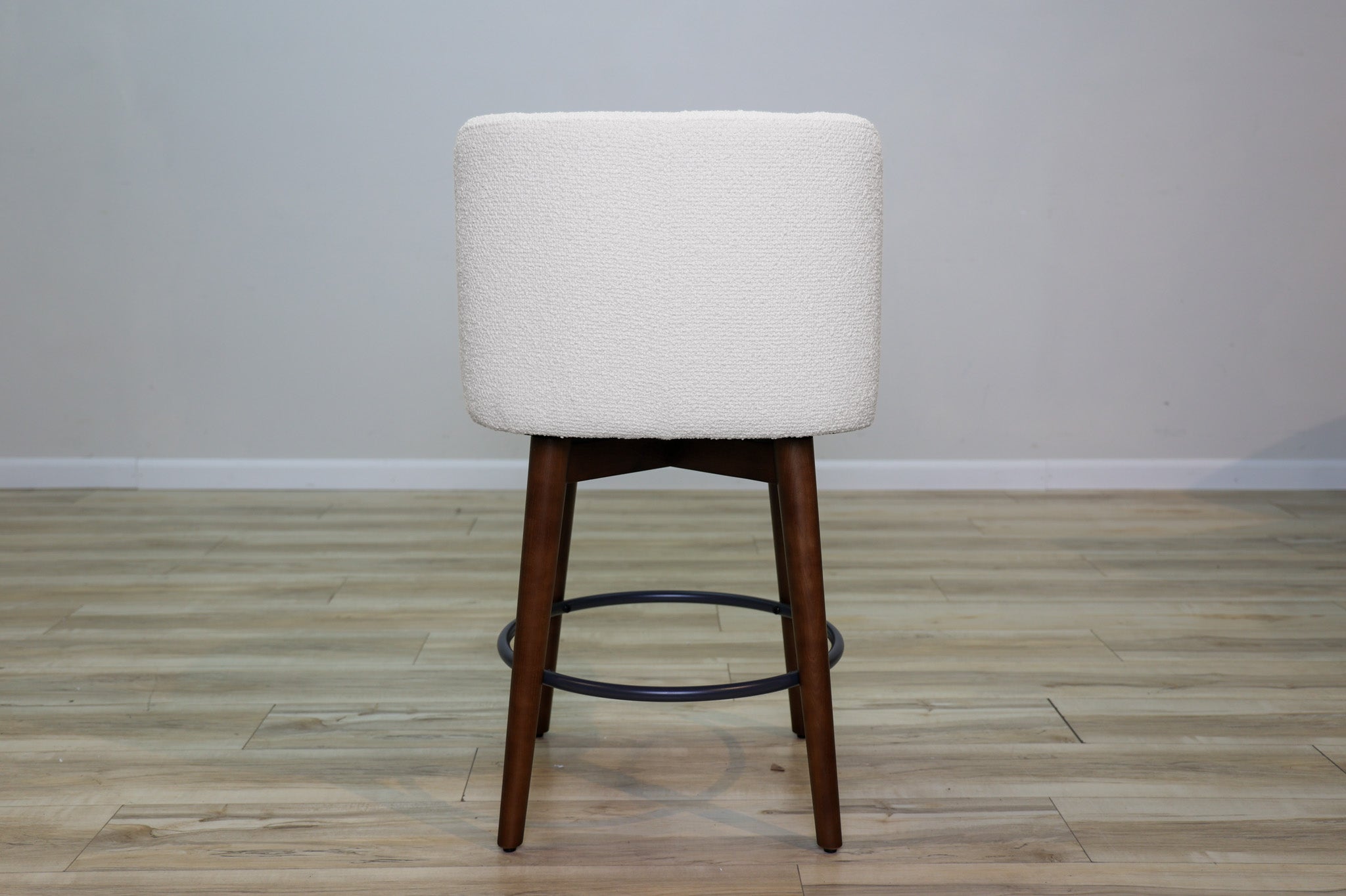 Avalon swivel counter stool in cream bouclé performance fabric with walnut wood legs and a black ring footrest, kitchen counter