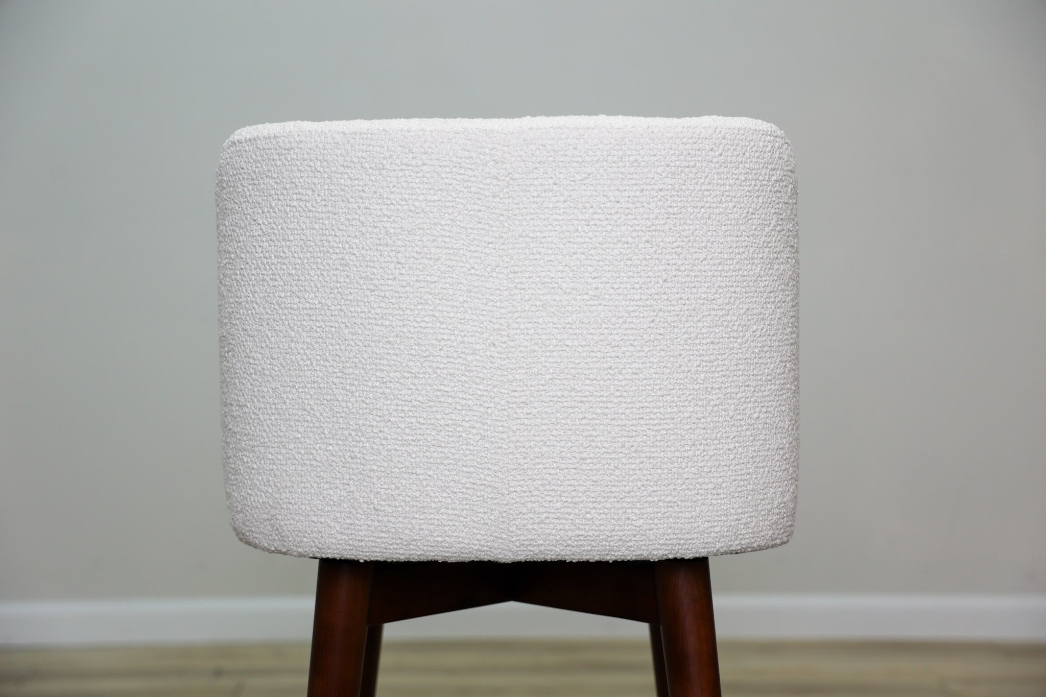 Avalon swivel counter stool in cream bouclé performance fabric with walnut wood legs and a black ring footrest, kitchen counter