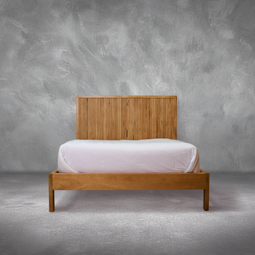 Fluted Bed with a hand-carved fluted mango wood headboard in natural finish, made up in a bedroom