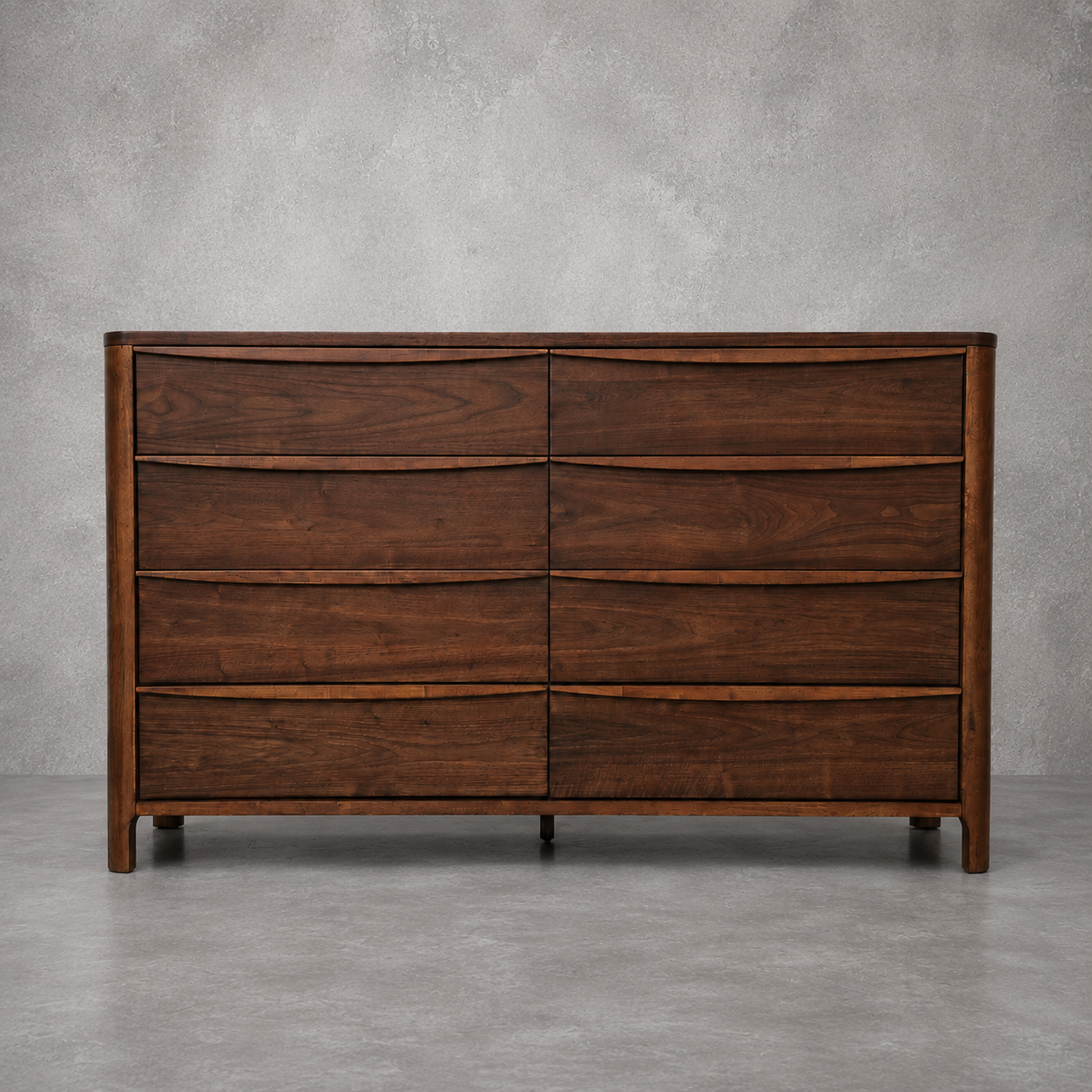 A mid-century modern wooden dresser with a dark brown walnut finish, featuring curved drawer fronts and a clean silhouette, set against a textured gray concrete wall and floor.