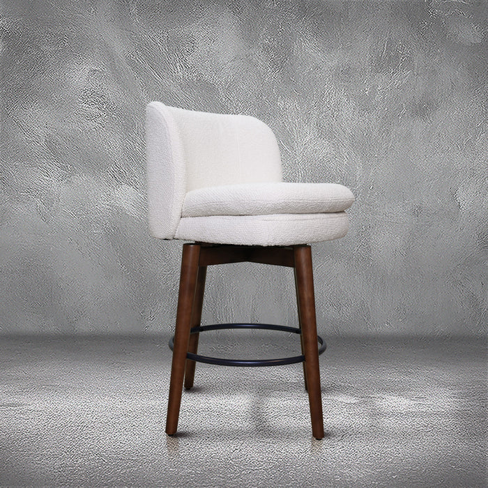 Avalon swivel counter stool in cream bouclé performance fabric with walnut wood legs and a black ring footrest, kitchen counter