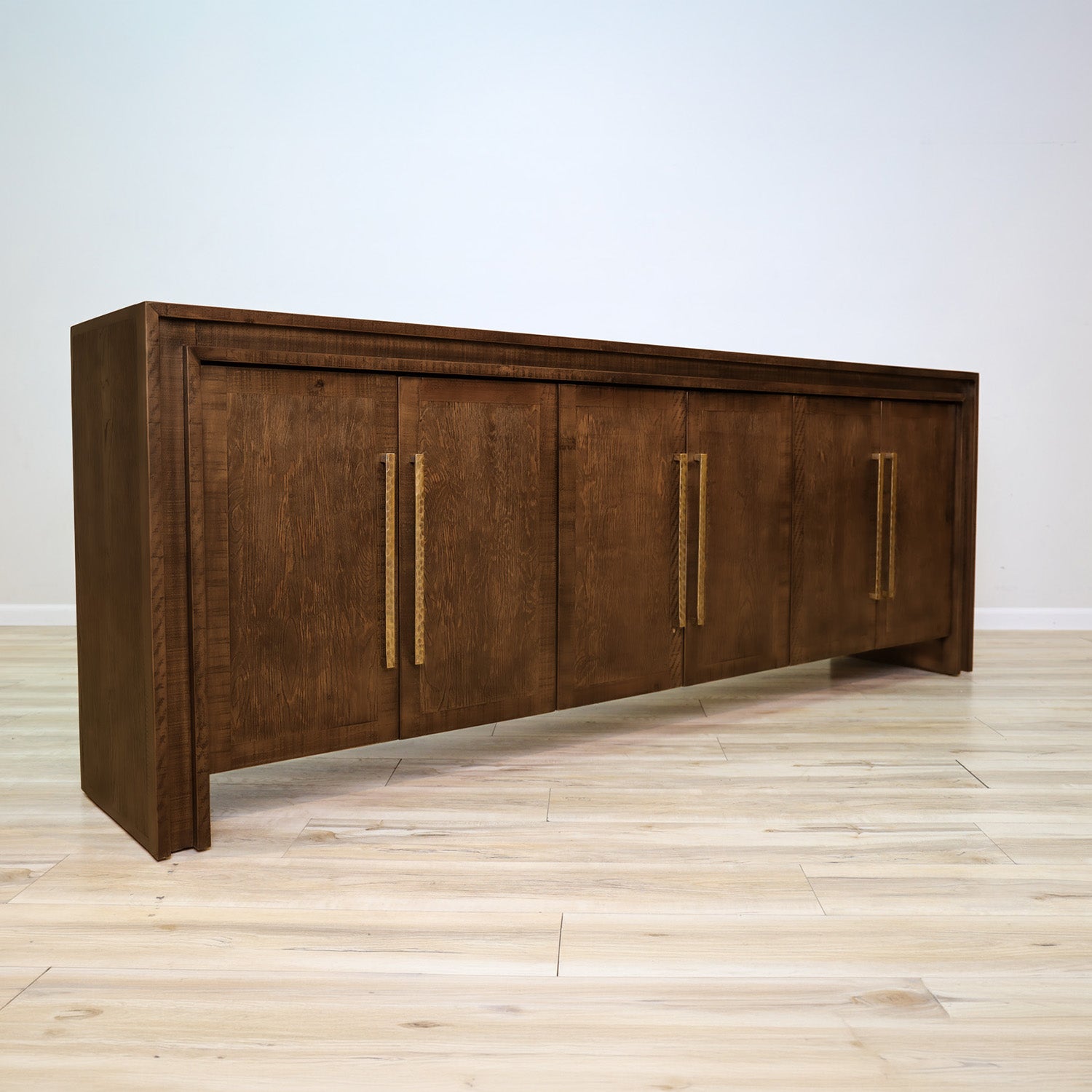 Manny 97-inch credenza in solid Mexican pine with six doors and hammered gold bar handles, living room