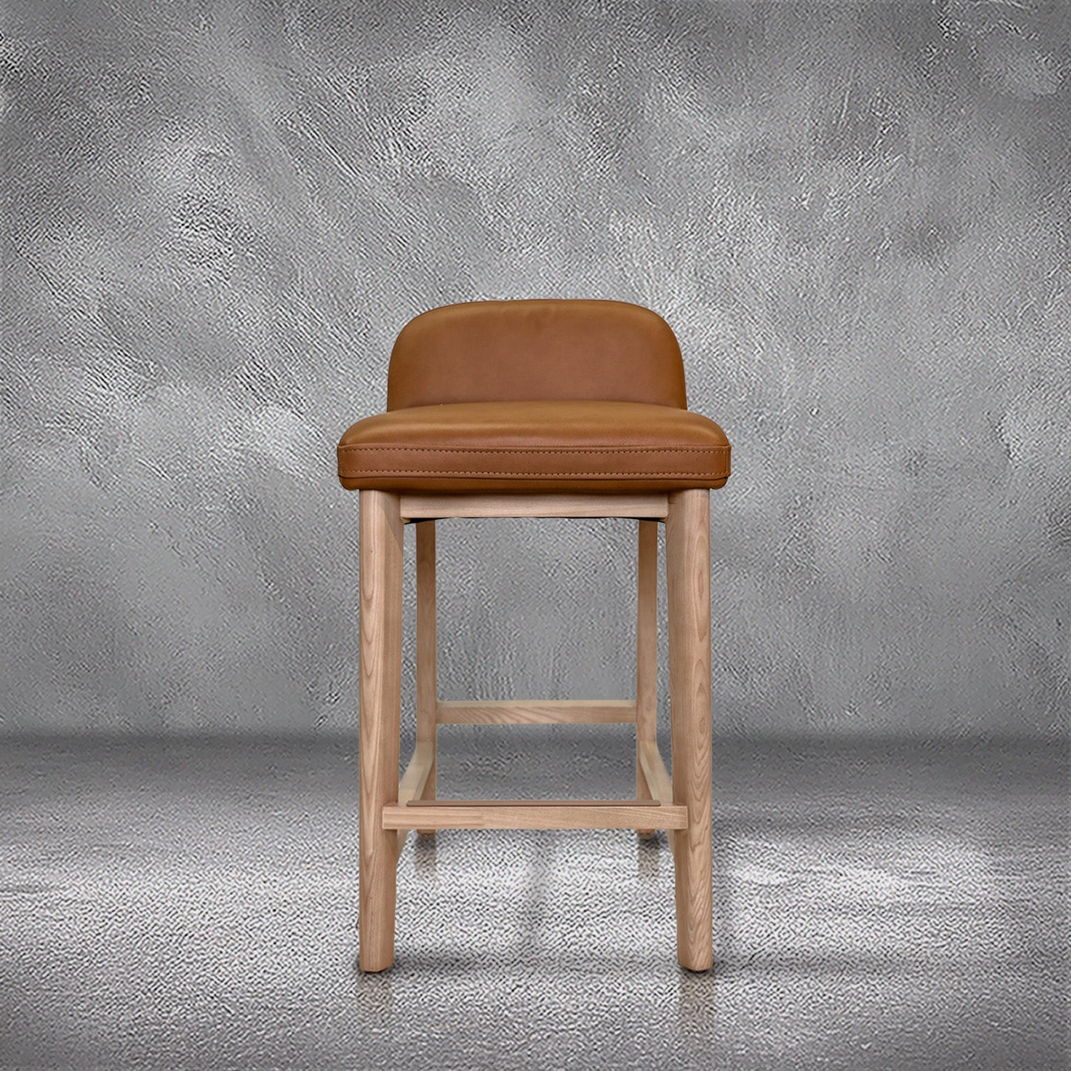 Sable counter stool in cognac leather with a low back and natural wood legs with stretchers, kitchen counter
