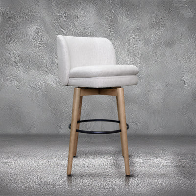 Tiffany swivel barstool in ivory Crypton fabric with natural wood legs and a black ring footrest, kitchen bar